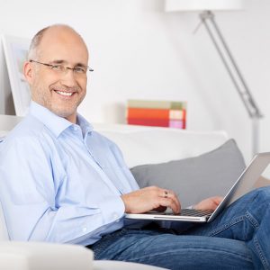 Man smiling with laptop on lap